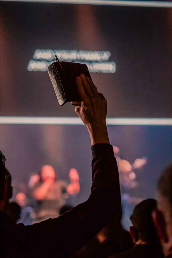 Pessoa levantando uma Bíblia durante culto